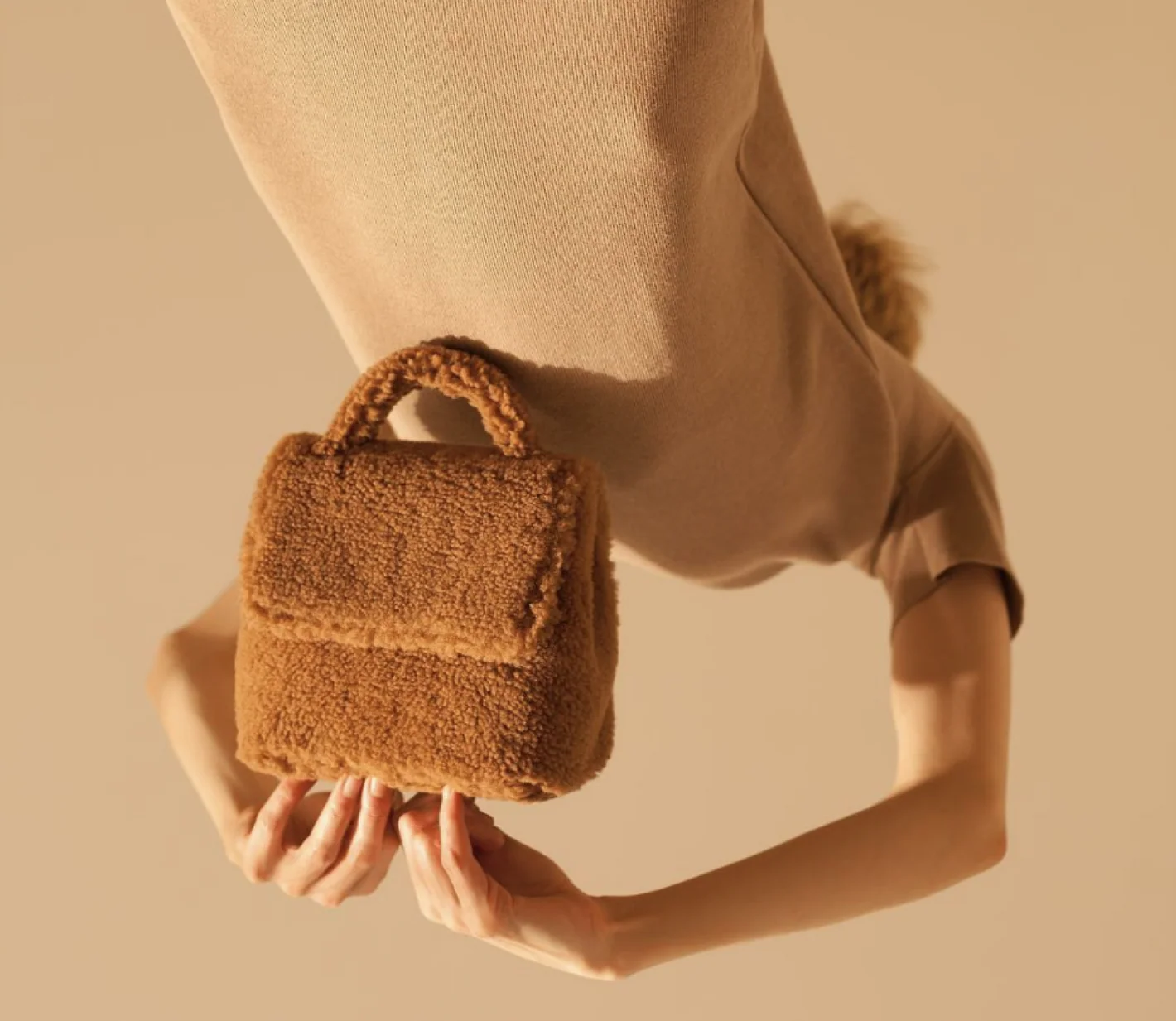 A woman holding a fuzzy brown handbag. 